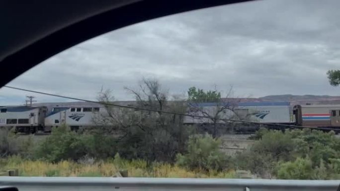 在科罗拉多州西部乡村慢动作视频系列中，在Amtrak大众运输旅客列车旁边行驶