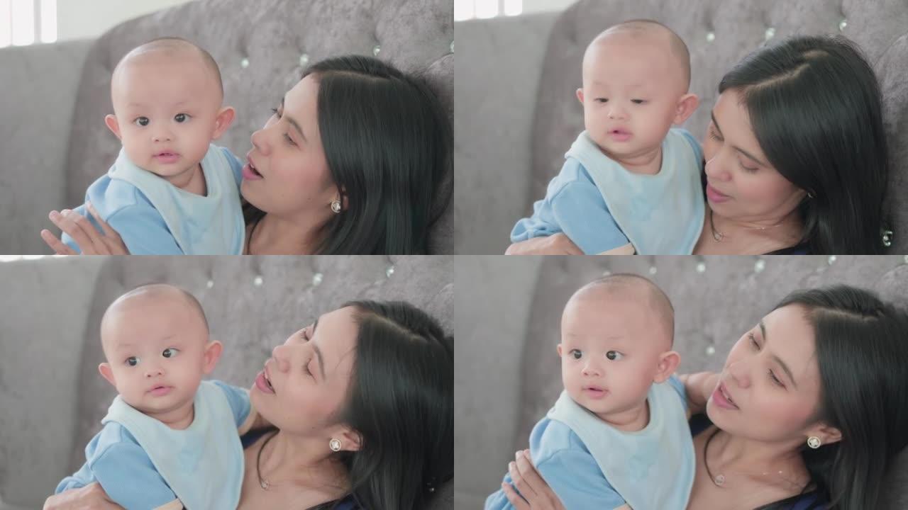 可爱的亚洲新生男婴与母亲坐在一起时笑容满面的真实照片。妈妈用手保重，用爱拥抱。天真的小新婴儿可爱。为
