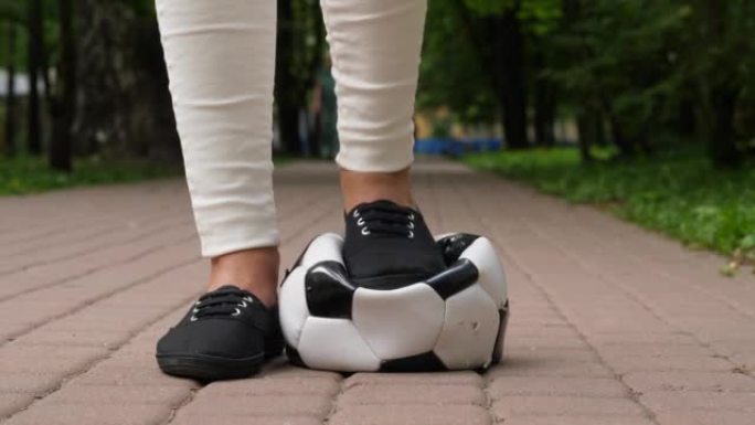 女孩把靴子放在足球上，把它压下去，低摄像机