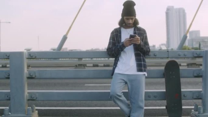 年轻的潮男站在街上用智能手机在社交媒体上聊天。