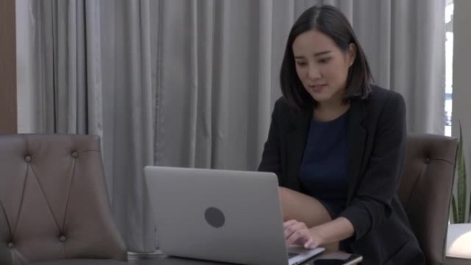 在明亮的休息区使用笔记本电脑的亚洲商业女性