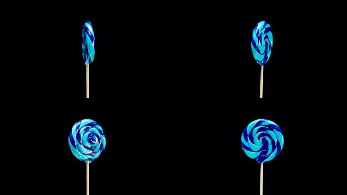 蓝色糖果棒棒糖在黑色背景上旋转。糖果棒螺旋复制空间