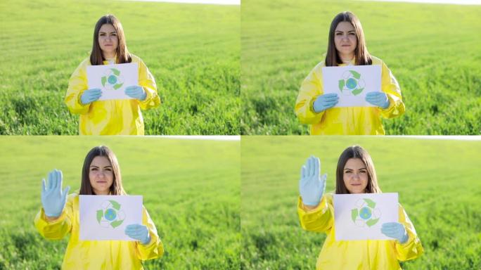 穿着工作服的人拿着纸呼吁拯救地球，同时站在日落时的绿色田野上，另一只手显示出停止并不污染地球的手势。