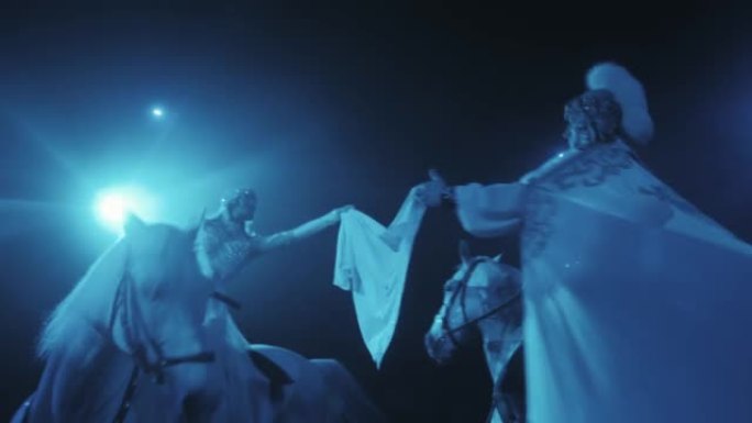 一个骑马的女孩和一个男人在美丽的灯光下手里拿着围巾围成一圈，马戏团表演