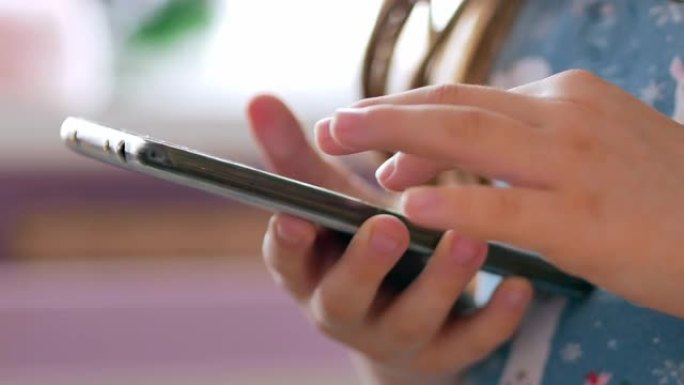 手机在一个孩子的手中，用手指点击屏幕，翻阅社交媒体页面或阅读信息，特写