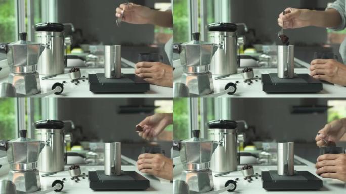 人们用手在不锈钢勺子上的粉状咖啡将烘焙过的咖啡倒入厨房家庭中数字秤冲泡意大利摩卡咖啡壶的杯子中。准备