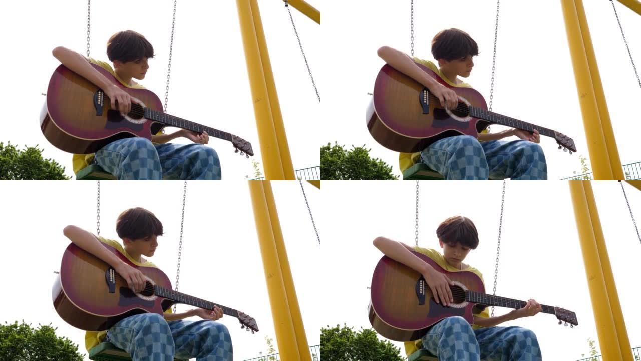 十几岁的男孩独自无聊地坐在秋千上摇摆在操场上弹吉他
