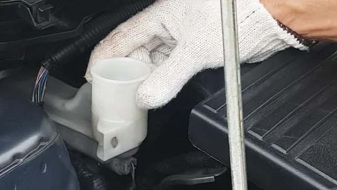 机械师正在打开制动液杯盖，以检查汽车发动机中的油位，slowmotion。