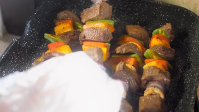 腌制的牛肉串和在烤架上准备的蔬菜。厨师把肉煎到其他地方