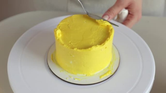 糕点厨师用烹饪锅铲特写在蛋糕上调出黄色奶油