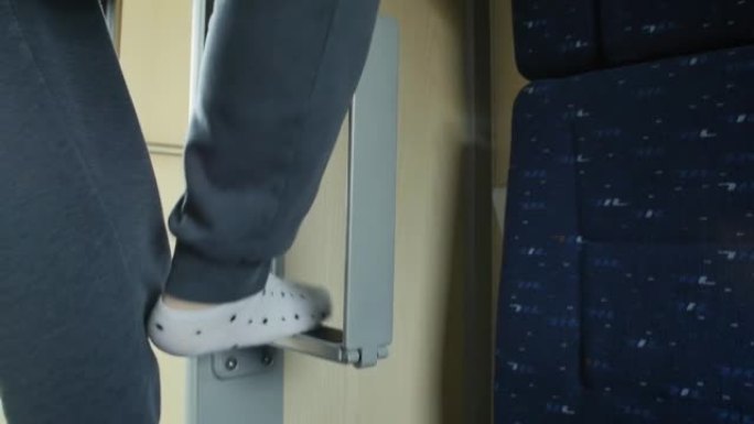 女人的脚踩在一个特殊的脚凳上，从车厢内的火车顶层爬下，将折叠的梯子折叠到原来的位置
