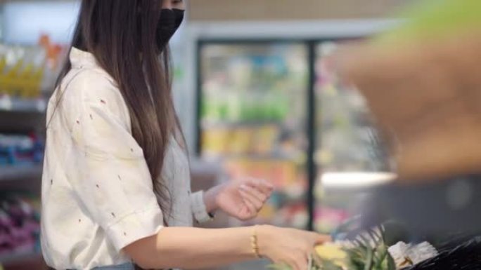 年轻亚洲妇女在杂货店购买新鲜水果和蔬菜或消费品