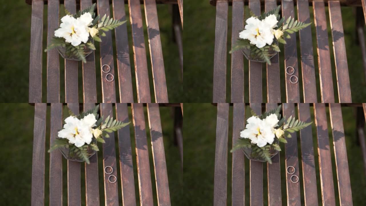 带花的花瓶站在棕色的木板条上，结婚戒指放在旁边