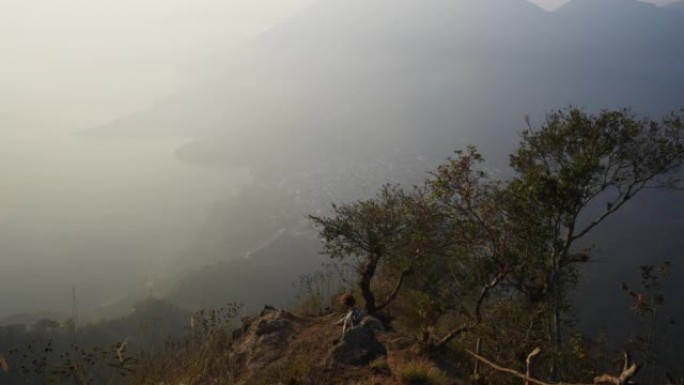 日落时分，男子站在危地马拉阿蒂特兰湖背景上的山上