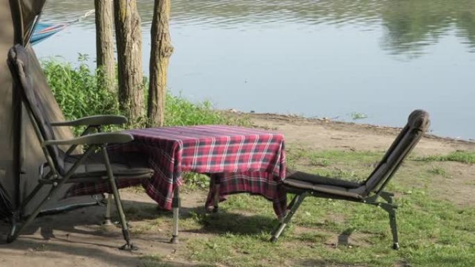 早上钓鲤鱼。河岸上的野营帐篷、桌椅