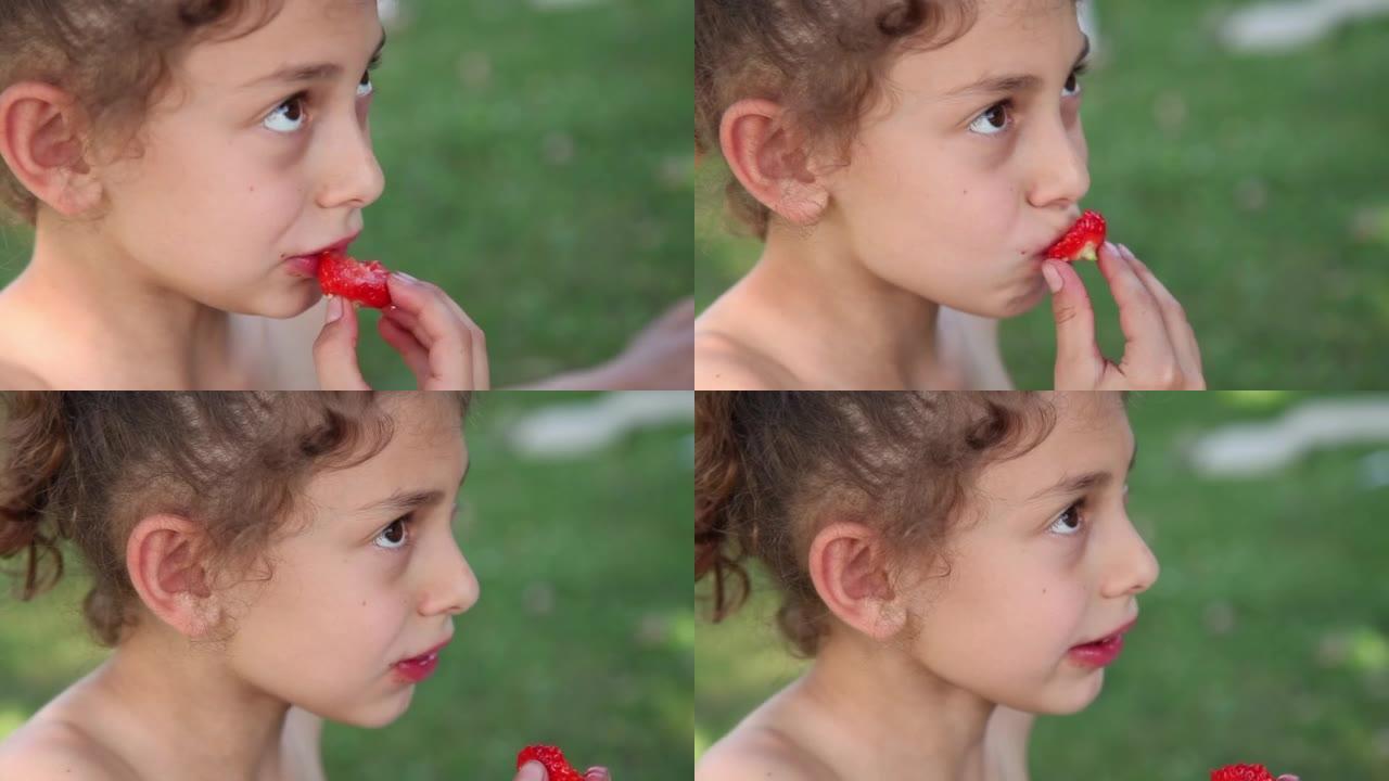 一个小女孩在公园吃草莓的侧面视图