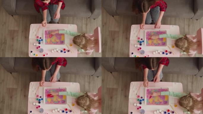 女孩把油漆和梳子混合在一起，和姐姐一起制作Ebru设计