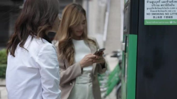 两名亚洲女商人用手机扫描二维码租自行车
