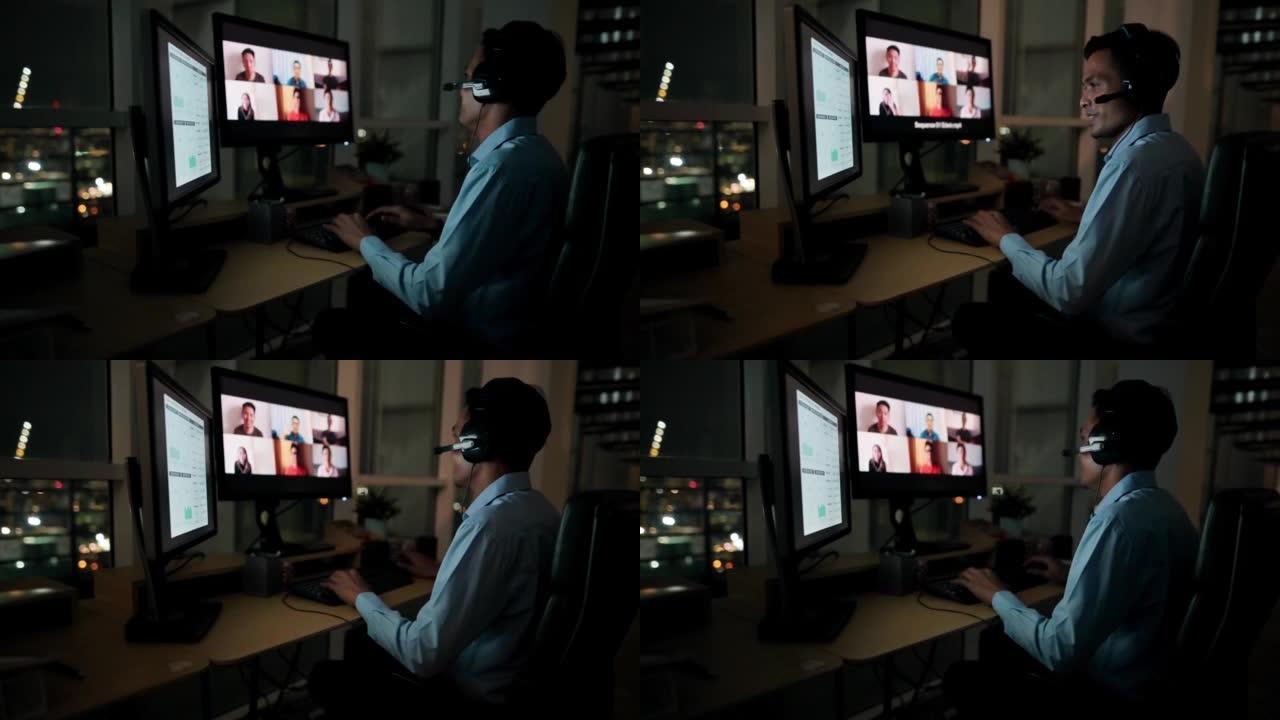 亚洲华裔男性白领视频通话在弱光下独自在办公室工作到很晚