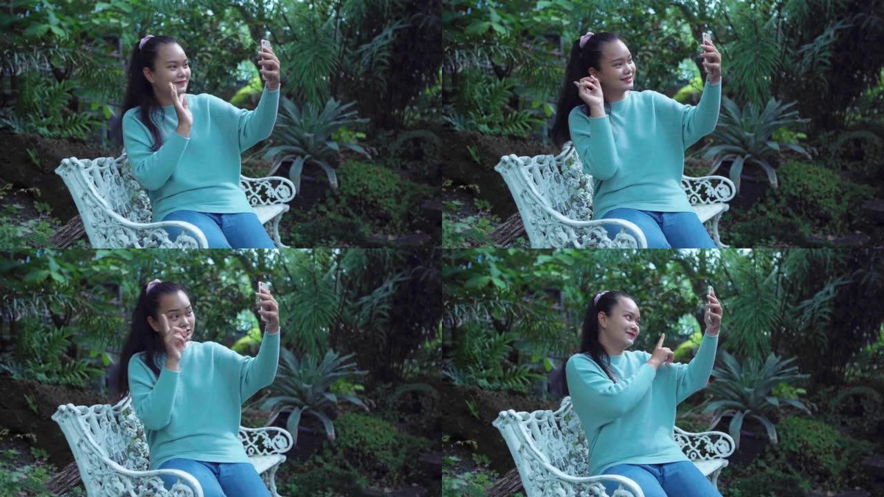 年轻的亚洲旅游女性在花园里使用智能手机进行自拍和广播，