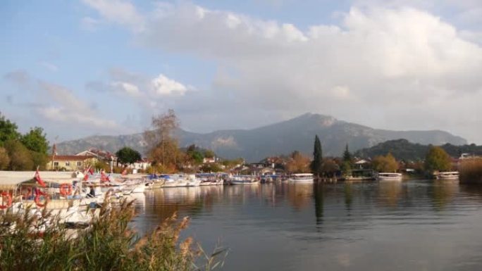 在土耳其里维埃拉 (Dalyan) 小镇上有许多船的平静河流的景色