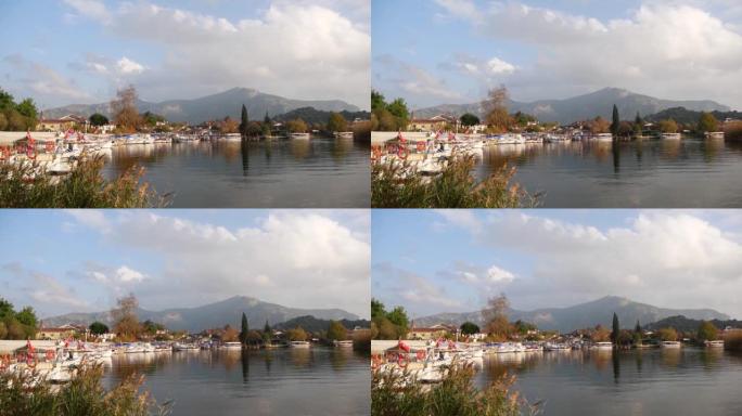 在土耳其里维埃拉 (Dalyan) 小镇上有许多船的平静河流的景色