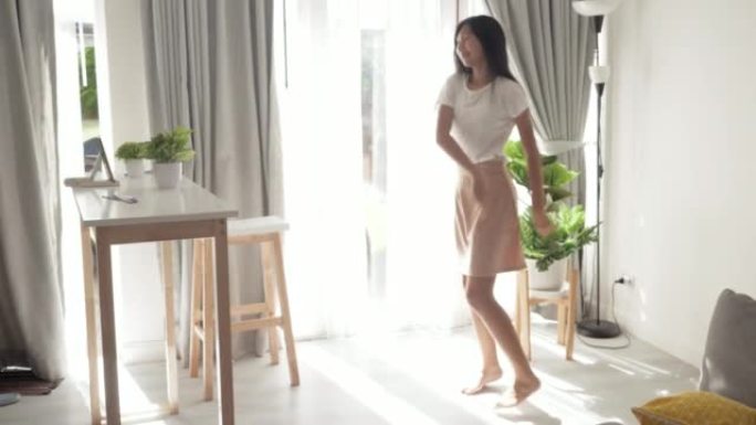 亚洲女孩跳舞，并通过智能手机在家中的窗户附近制作病毒视频，生活方式概念。