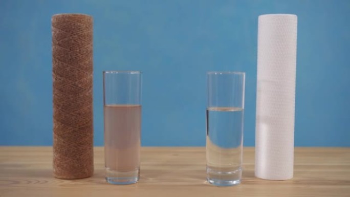 水净化的概念思想，带有脏净水的眼镜站在桌子上，带有蓝色背景上的墨盒