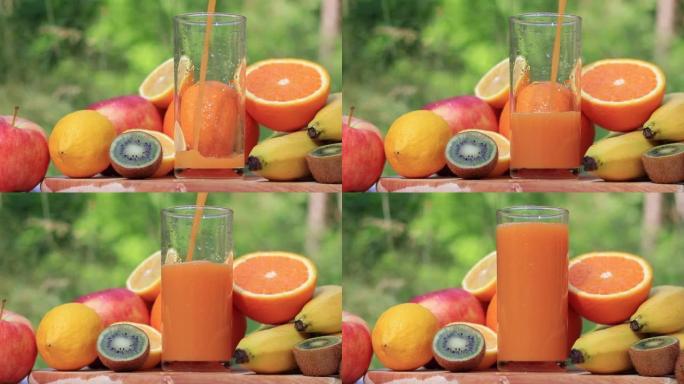 将多种维生素汁倒入大自然背景下的高玻璃杯中