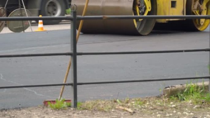 黄色压路机在铺设沥青的同时行驶在道路上。建设新路
