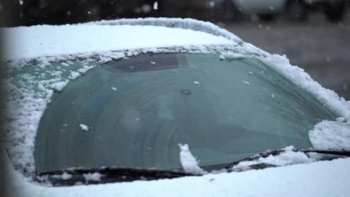冬天。雪地里的车。从汽车挡风玻璃上刮雪和冰。挡风玻璃雨刷在前一天晚上升起，以防止它们被冻结
