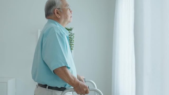 亚洲老年老人病人在疗养院用助行器或拐杖缓慢行走。有吸引力的年长男性在家里独自做物理治疗时感到快乐。医