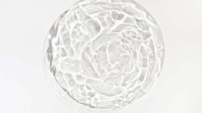 在Petri玻璃碗中带有气泡的透明化妆品凝胶流体的旋转。宏丸血清、乳膏、透明质酸。有机化妆品，药品。