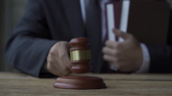 4k慢动作视频律师拿着一本书法律锤在律师事务所的桌子上，啊正义的概念。