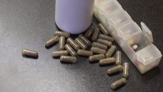 明胶胶囊中的药物。散落在桌子上。附近有一个装满药丸的药丸盒。特写。