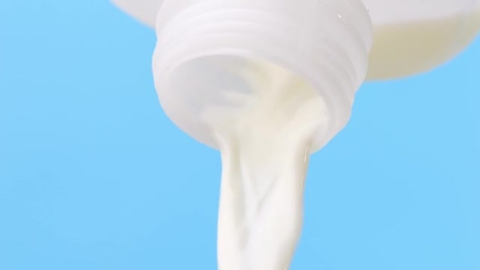 将加仑瓶新鲜牛奶倒在蓝色背景上。