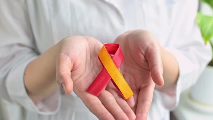 世界肝炎日。女人医生手里拿着红色的黄色丝带。预防和治疗病毒性肝炎的意识。肝癌。世界癌症日。全高清