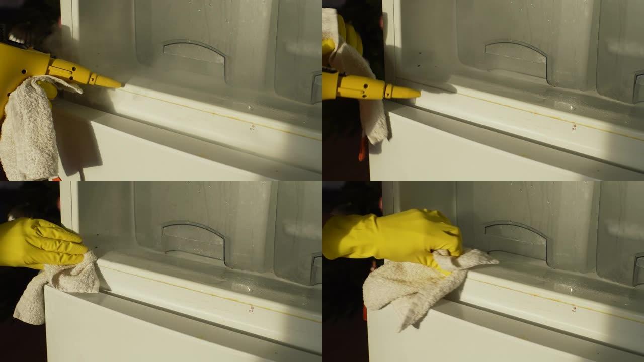 用黄色手套关闭无法辨认的男性家庭主妇的手，用蒸汽清洁器清洁空冰箱，用布洗架子做家务。