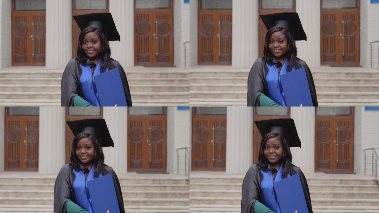 穿着黑色地幔的害羞的非裔美国女毕业生穿着地幔，拥有大学背景的研究生文凭。一个重要的事件。年轻专家