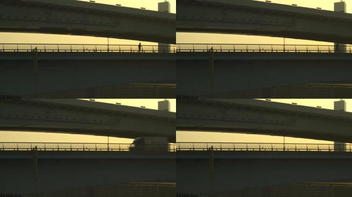 黄昏时桥的轮廓。人们正在过桥。跑步的人