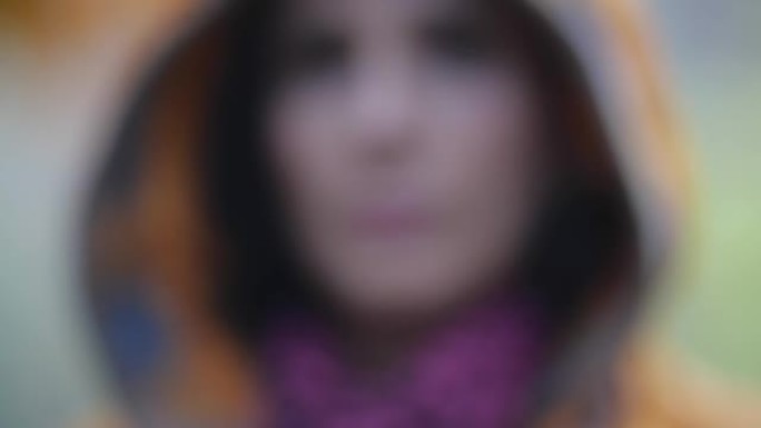 浅浅的焦点肖像，一个无法辨认的黑发女人，有着长长的黑发。她用秋天的橡树叶遮住脸，手里拿着它向相机展示
