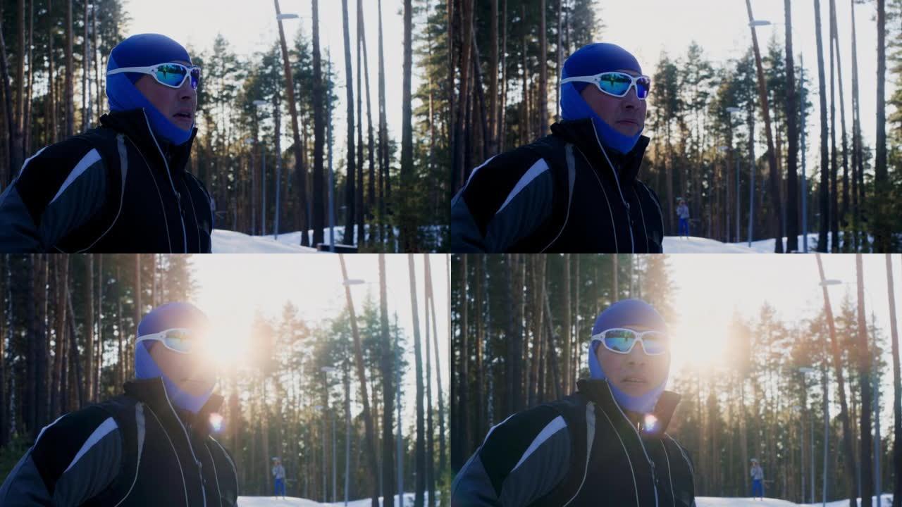 男子在冬季森林滑雪时看着日落的天空