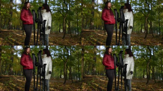 北欧人在森林中行走的特写杆，背景是模糊的成熟女性。自信的高加索朋友聊天分享谣言站在户外秋季公园训练休
