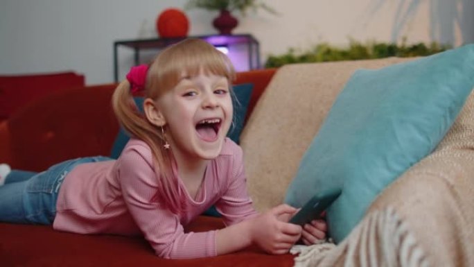 快乐的小女孩用手机玩网络游戏，庆祝大胜，好消息