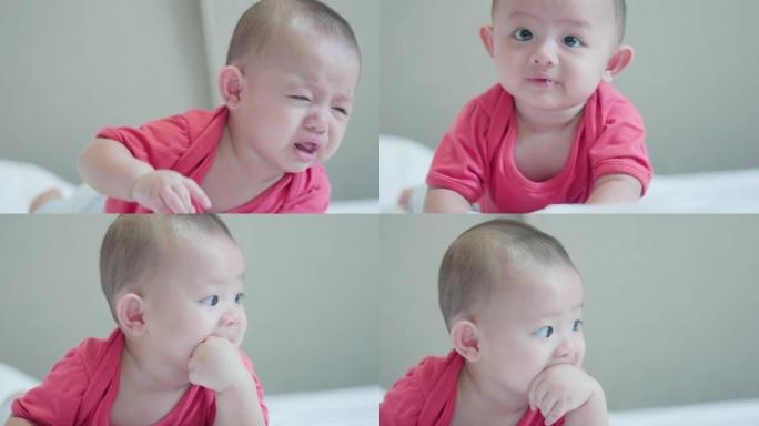 可爱的亚洲新生婴儿穿着红色衬衫躺在白色床上爬行，婴儿开始哭泣。