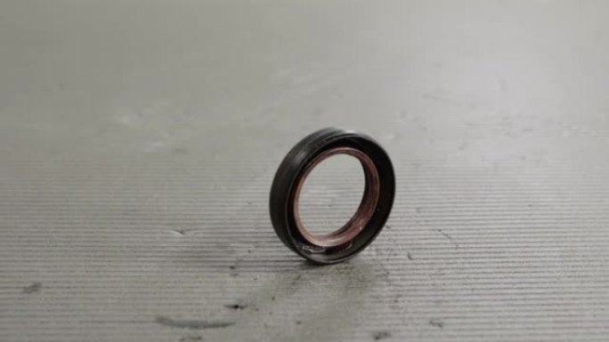 Camshaft oil seal in a car engine on a gray backgr