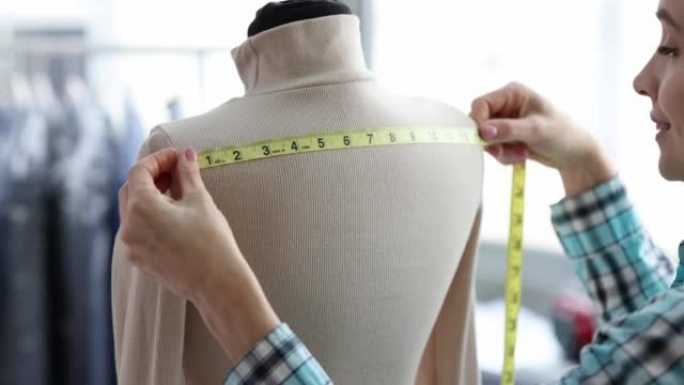 女裁缝从人体模型上的衣服中进行测量