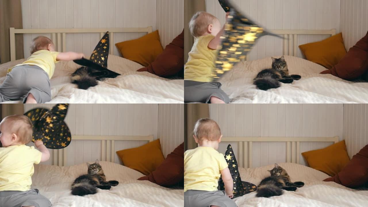 一岁的孩子在舒适的卧室背景下与猫玩耍。可爱的小女孩和小猫在家里，戴着女巫的帽子，万圣节的时候。万圣节