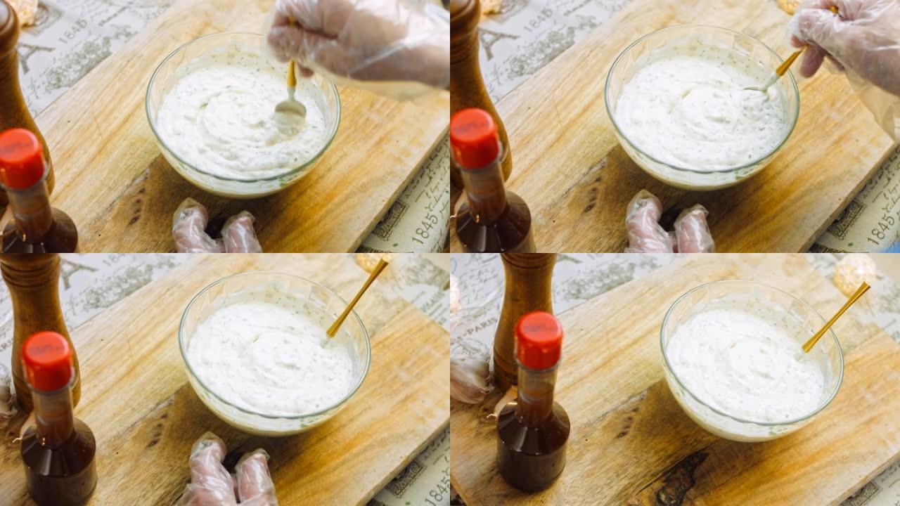 厨师将酸奶与酸奶油和蛋黄酱混合到牧场酱的配料中。使用金勺
