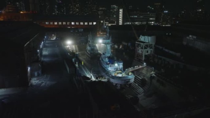 在干船坞中滑动和平移船只的航拍画面。晚上修理船只。美国纽约市曼哈顿